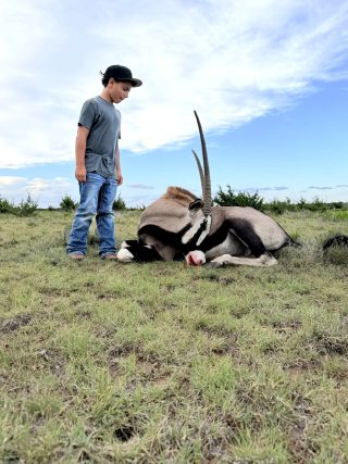A young hunter stands beside a gemsbok taken at BarBell Ranch in Sweetwater, TX.