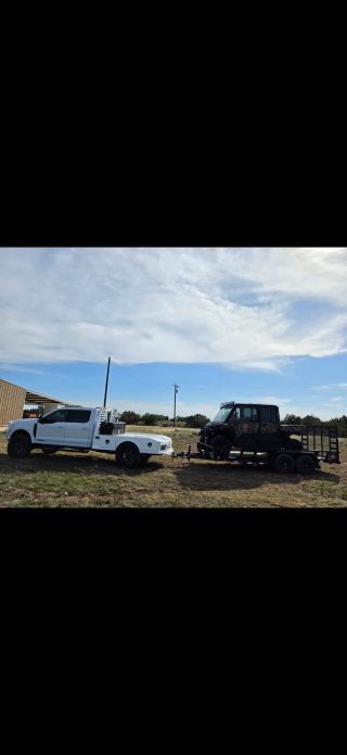 A flatbed truck tows a utility vehicle on a trailer at BarBell Ranch in Sweetwater, TX.