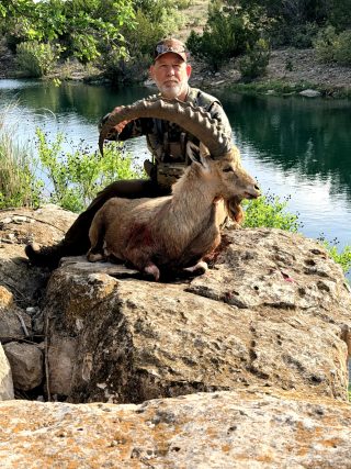 Hunter and trophy Nubian Ibex at BarBell Ranch in Sweetwater, TX, by a tranquil pond.