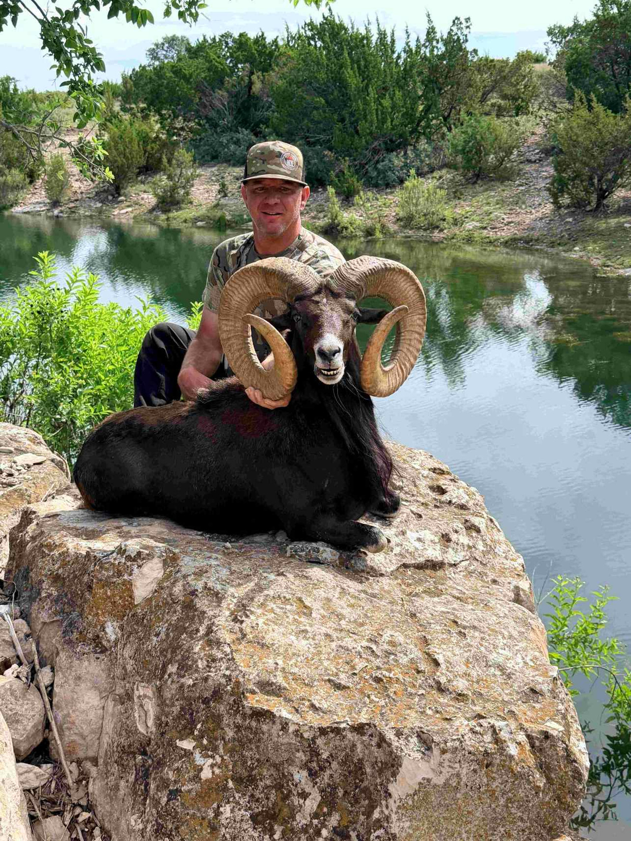 Hunter with a Midnight Urial taken at BarBell Ranch in Sweetwater, TX, beside still water.