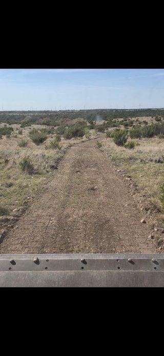 Texas hunting ranch road winding through West Texas brush country.