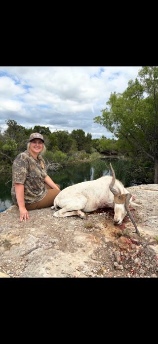 Hunter with a trophy addax taken at BarBell Ranch in Sweetwater, TX, by a tranquil pond.